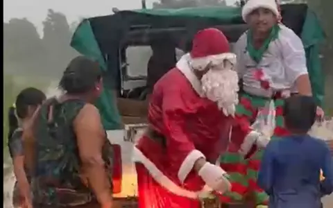 Papá Noel entregando regalos en medio de la lluvia