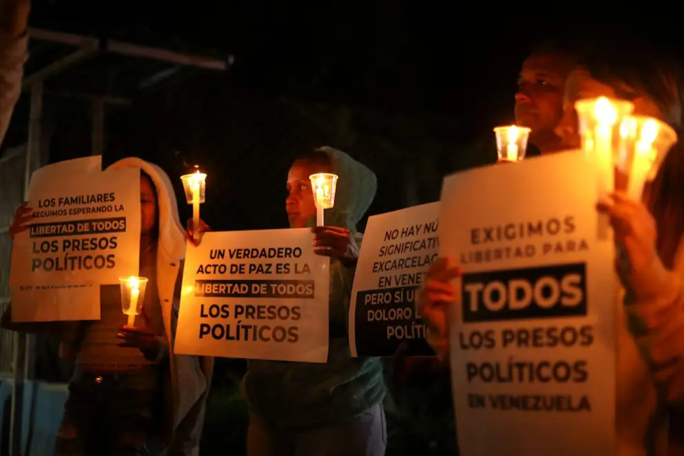 Familiares de presos políticos sostienen carteles y velas durante una vigilia afuera del centro penitenciario Rodeo.