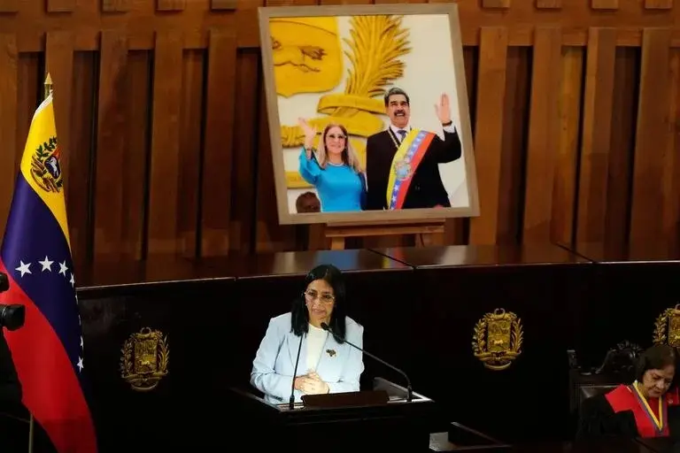 Delcy Rodriguez habla frente a un retrato de Nicolás Maduro y su mujer
