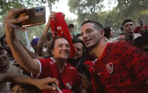El mediocampista Iván Marcone posa con una hincha del rojo en la llegada del equipo de Avellaneda a Mendoza.