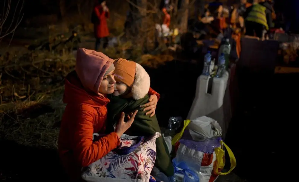 Una mujer carga a una niña después de cruzar la frontera de Ucrania hacia Rumania, en Siret, Rumania.