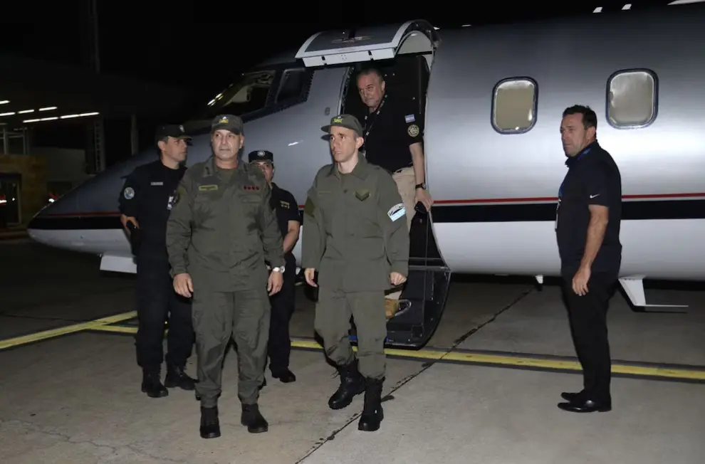 Nahuel Gallo desciende de una aeronave oficial en el marco de un operativo de seguridad, acompañado por personal uniformado.