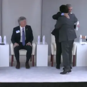 Con las cámaras encendidas: Sáenz subió al escenario y rompió protocolo para volver a saludar a Caputo en pleno inicio de un panel