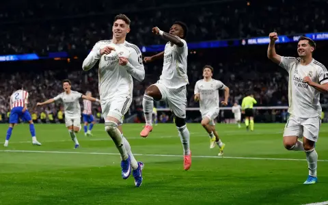 Federico Valverde celebra su golazo señalando su escudo, Vinicius lo sigue en su festejo desde atrás, en la victoria del Real en el clásico de Madrid.