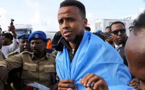 El árbitro somalí escoltado por las fuerzas de seguridad en la llegada a su país