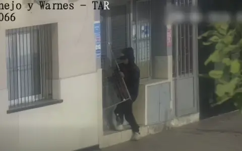 El ladrón rompiendo la puerta principal del comercio.