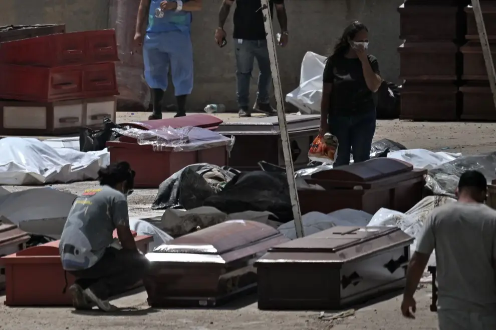 Habitantes locales permanecen entre víctimas y ataúdes en La Guaira, estado venezolano de La Guaira, el 29 de junio de 2026
JUAN BARRETO - AFP