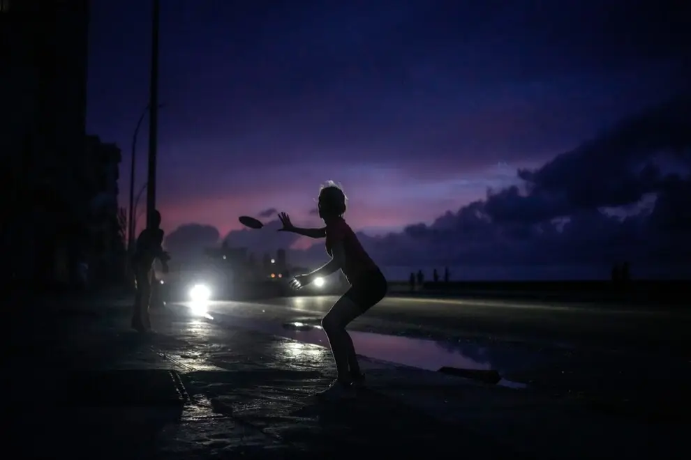 Una mujer se prepara para atrapar un frisbee durante un gran apagón tras un problema en una importante central eléctrica en La Habana, Cuba
