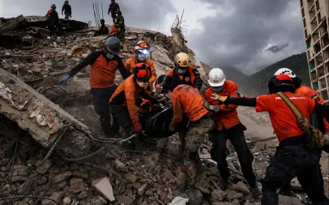 Equipos de rescate trasladan una bolsa con el cuerpo de una víctima entre los escombros de un edificio colapsado