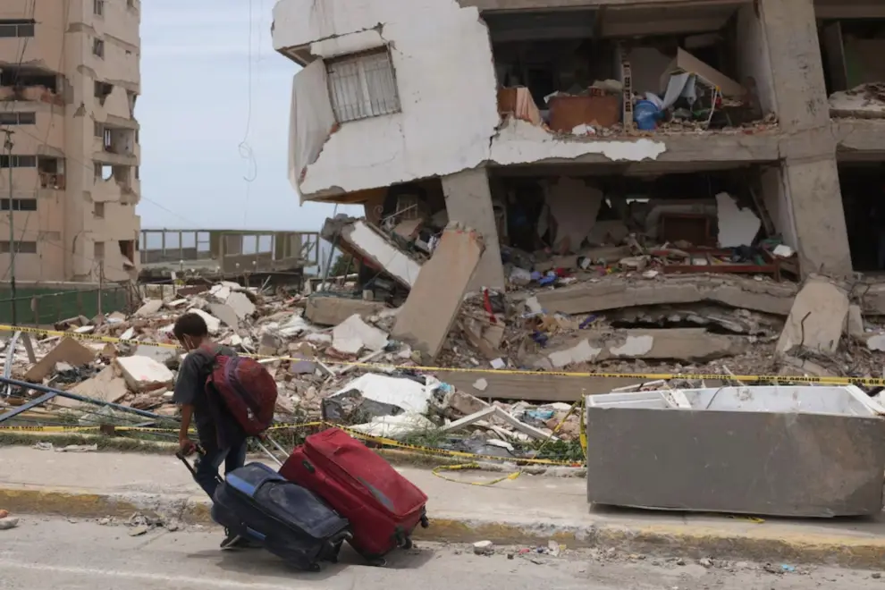Un edificio de la Gran Misión Vivienda Venezuela dañado por los terremotos del 24 de junio en Catia La Mar. Frente a él, un niño carga equipaje mientr
