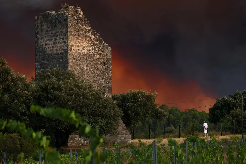Un hombre observa cómo se eleva el humo cerca de una ruina en el pueblo de Cotignac