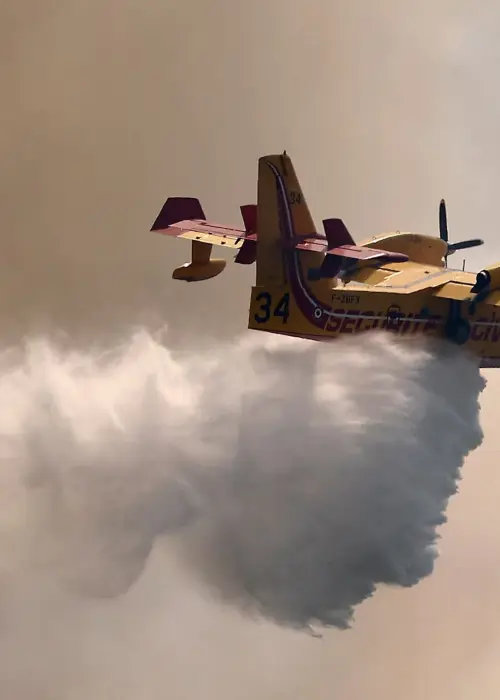 Un avión de extinción de incendios Canadair arroja agua para combatir un incendio forestal en el bosque comunal de Fox-Amphoux